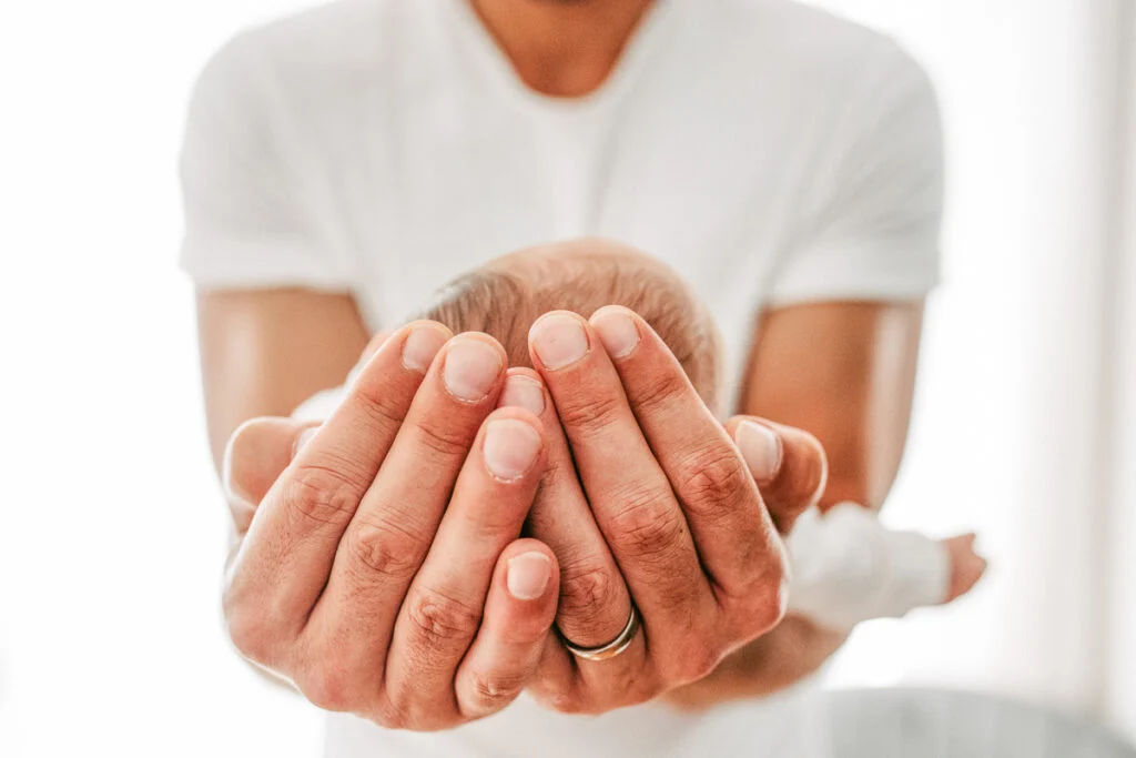 Ein kleines Baby liegt geborgen in den Händen eines Erwachsenen